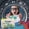 A woman is screaming in frustration as she holds up a stained white shirt inside a washing machine drum. A box of Heitmann Gallseife (gall soap) is in the foreground. Produktbild-Vorschau