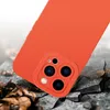 A close-up shot of an orange phone case, showing the camera module, resting on a cracked surface with fallen leaves. Produktbild-Vorschau