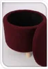 A burgundy upholstered round ottoman with a black interior and three wooden legs is shown from a side angle. Podgląd zdjęcia produktu