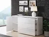 A white dresser with open drawers and a cabinet door, placed against a dark textured wall with framed pictures and a lamp. Anteprima dell’immagine prodotto