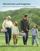 A family walking in a grassy field with trees in the background, carrying picnic blankets. Produktbild-Vorschau