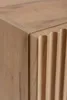 A close-up shot of the corner of a wooden cabinet with a fluted design. Náhľad obrázku produktu