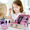 Two young girls are playing with a toy makeup set, with one applying makeup to the other. Voir les images du produit