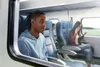 People sitting on a train, one person wearing earbuds. Anteprima dell’immagine prodotto