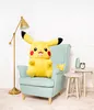 A large Pikachu plush toy sits in a light blue armchair next to a floor lamp and small side tables. Produktbild-Vorschau