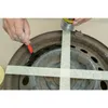 A person is using a brush to apply a product to a rusty wheel rim, which is taped off with masking tape. Produktbild-Vorschau