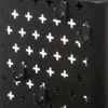A close-up view of a black metal pegboard with a pattern of plus-shaped holes and several black hooks attached. Podgląd zdjęcia produktu