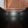A top-down view of a shower enclosure with glass doors and silver metal framing, set against a backdrop of dark tiled walls and floor, with wooden flooring visible at the top. Voir les images du produit