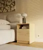 A bedside table with a lamp and books next to a bed. Anteprima dell’immagine prodotto