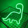 A green neon dinosaur light is displayed inside a black wire basket against a green background. Podgląd zdjęcia produktu