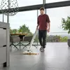 A man is using a cordless floor cleaner in a modern living room with large windows overlooking a scenic view. Anteprima dell’immagine prodotto