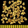 A collection of gold nuggets on a black background with a ruler at the bottom. Produktbild-Vorschau