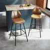 Two brown bar stools with backrests are placed in a modern kitchen setting, next to a kitchen island with a marble countertop. The lighting creates shadows on the floor. Podgląd zdjęcia produktu