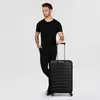 A man stands next to a black suitcase. Produktbild-Vorschau