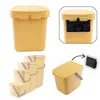 A collage of images showing a yellow plastic waste bin with a lid and handle, along with its mounting bracket and a set of nested bins. Produktbild-Vorschau