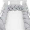 A light gray braided crib bumper is shown inside a white crib. Náhľad obrázku produktu