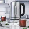 A modern kitchen counter with a stainless steel electric kettle and two cups of tea. Produktbild-Vorschau