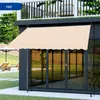 A beige awning is extended over a glass door on a modern building, with lounge chairs and an umbrella visible in the background. Náhľad obrázku produktu