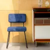 A blue corduroy chair is placed next to a vintage-style cabinet with a wooden top and white doors. Voir les images du produit