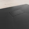 A close-up, angled view of a black shower tray with a textured surface and a rectangular drain cover. Produktbild-Vorschau
