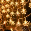 A string of snowflake-shaped lights is draped around a window or doorway, with a pinecone and greenery in the foreground. Produktbild-Vorschau