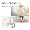 A woman is sitting in an office chair, listening to music with headphones. The chair has an adjustable footrest and armrests. A diagram shows the range of motion for the armrests. Náhľad obrázku produktu