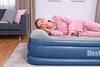 A woman sleeping on an inflatable mattress in a room with a sofa and curtains. Produktbild-Vorschau