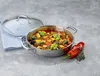 A stainless steel serving pan filled with ratatouille, a glass lid, a blue napkin, a red pepper, and herbs are arranged on a gray surface. Podgląd zdjęcia produktu