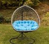 A hanging egg chair with a blue cushion sits on a grassy lawn surrounded by trees with autumn foliage. Anteprima dell’immagine prodotto