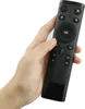 A hand holding a black remote control against a white background. Voir les images du produit