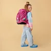 A young girl is wearing a backpack and smiling. Náhled obrázku produktu