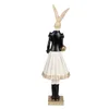 A figurine of a rabbit wearing a black jacket, white skirt, and black boots, holding a gold purse. Náhľad obrázku produktu
