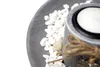 A close-up of a decorative tray with white stones and a candle holder. Náhled obrázku produktu