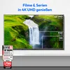 A television screen displaying a waterfall scene with resolution comparisons, placed on a shelf with marketing badges below. Produktbild-Vorschau