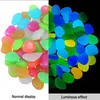 The image shows a split view of colorful stones. The left side displays the stones under normal lighting, while the right side shows their luminous effect in the dark. Produktbild-Vorschau