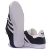 A pair of navy blue Adidas Gazelle sneakers shown from the side and underneath. Produktbild-Vorschau