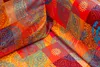 A close-up view of a colorful, patterned fabric with a patchwork design. Produktbild-Vorschau