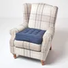 A dark blue cushion is placed on a beige and light blue plaid armchair. Náhled obrázku produktu