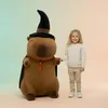 A young girl stands next to a large plush capybara wearing a wizard hat and cape. Náhľad obrázku produktu