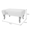 A white ottoman with decorative legs is shown with dimensions indicated by lines and text. Voir les images du produit