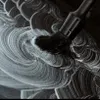 A black detailing brush is being used to apply white foam or paste in a swirling pattern on a dark surface. Anteprima dell’immagine prodotto