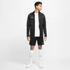 A man wearing a black Nike tracksuit stands against a white background. Produktbild-Vorschau