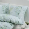 A close-up view of a bed with pillows and a duvet cover featuring a green leaf pattern. Produktbild-Vorschau