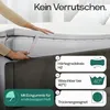 A person is shown placing a mattress topper onto a mattress. Produktbild-Vorschau