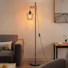 A floor lamp with a vintage industrial design is placed next to a sofa in a living room. Produktbild-Vorschau