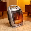 A ceramic heater is shown on a rug in a room with wooden furniture in the background. Podgląd zdjęcia produktu