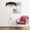 A modern living room scene with a pink armchair, a side table with a vase and decorative object, and a large abstract painting on the wall, all illuminated by a black and crystal chandelier. Produktbild-Vorschau