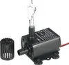 A small black submersible water pump with water spraying from its outlet, shown with a separate filter attachment. Produktbild-Vorschau
