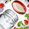 A glass jar with a red lid and various vegetables floating around it. Podgląd zdjęcia produktu