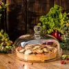 A glass cloche covers a vegetable tart on a wooden table, surrounded by fresh herbs and berries. Náhľad obrázku produktu